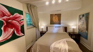 Una habitación de hotel con una cama grande, dos mesitas de noche, una ventana con cortinas y tres lámparas de pared.