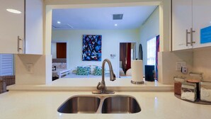 A modern kitchen with a double sink, a stainless steel faucet, and a view into the adjacent living area. - Suarez Art Stay, 3BR Miami Oasis with Parking (Miami)
