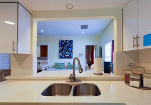 A modern kitchen with a double sink, a stainless steel faucet, and a view into the adjacent living area. - Suarez Art Stay, 3BR Miami Oasis with Parking (Miami)