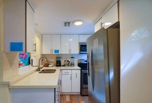 A modern kitchen with white cabinets, stainless steel appliances, a microwave, and a dishwasher. - Suarez Art Stay, 3BR Miami Oasis with Parking (Miami)