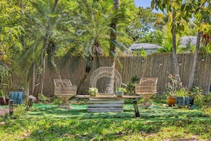 A garden with a circular seating area, a thatched fence, and various plants. - Suarez Art Stay, 3BR Miami Oasis with Parking (Miami)