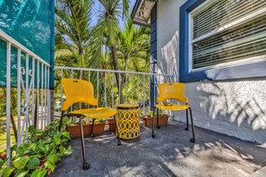 A balcony with two yellow chairs and a small round table, surrounded by potted plants and a metal railing. - Suarez Art Stay, 3BR Miami Oasis with Parking (Miami)