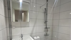 A modern bathroom with a white sink, toilet, and shower. - Stay Sollentuna (Sollentuna)