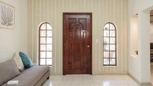 A room with a wooden door, two arched windows, a beige sofa with cushions, and a framed picture on the wall. - Residence with swimming pool and large patio for families (Monterrey)