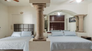 A hotel room with two beds, a large column, a ceiling fan, and a wooden cabinet. - Residence with swimming pool and large patio for families (Monterrey)