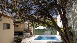 A swimming pool with a tiled deck, surrounded by a stone patio, a lounge area with a table and chairs, and a pergola with hanging lights. - Residence with swimming pool and large patio for families (Monterrey)