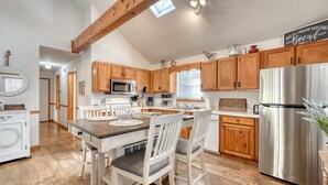 A kitchen with wooden cabinets, a stainless steel refrigerator, a dining table with chairs, and a skylight. - Steps to Shooting Creek (Hayesville)