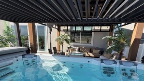 A swimming pool with a 'SWIM' sign, surrounded by a covered patio area with seating and potted plants. - Magical Mountain-View Retreat SwimSpa-Hot Tub , Fire pit & Cozy Living Spaces  (Salem)