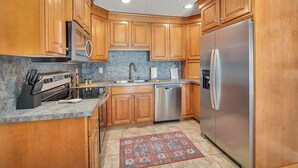 A kitchen with wooden cabinets, stainless steel appliances, a built-in oven, and a dishwasher.