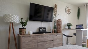 A modern bedroom with a large bed, a wooden dresser, a flat-screen TV, a laptop, and a desk with a chair. - Studio Paradis Le Gosier - Sea view, close to beaches & restaurants (Le Gosier)