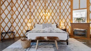 Ein gemütliches Schlafzimmer mit einem Bett, Nachttischlampen, einem Kamin und einem gewebten Korb.