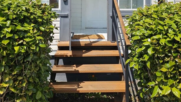 Et hus med en hoveddør, en trætrap og en lille veranda.