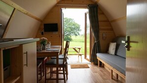 Een gezellig, houten interieur met een eethoek, een bank en een aan de muur bevestigde televisie.