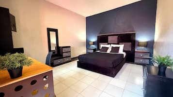 Un dormitorio moderno con una cama grande, un aparador, un espejo y dos mesitas de noche con lámparas.