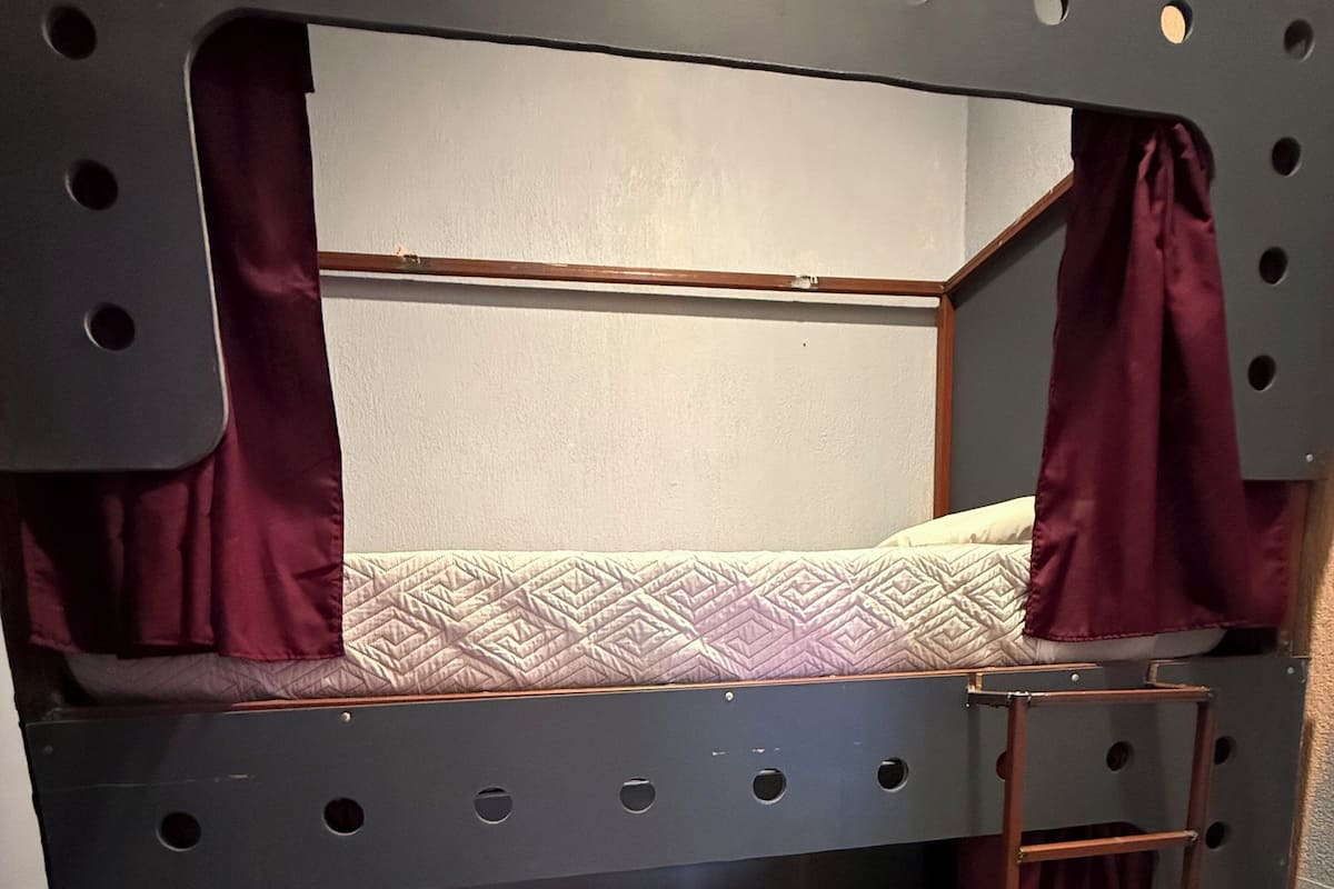 A bunk bed with a ladder, a mattress, and a headboard.
