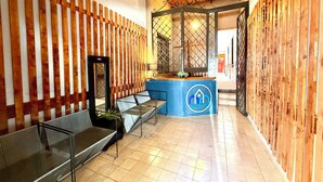 A reception area with a blue counter, metal benches, and a wooden wall. - RMS Hostal - Roma Norte (Mexico City)