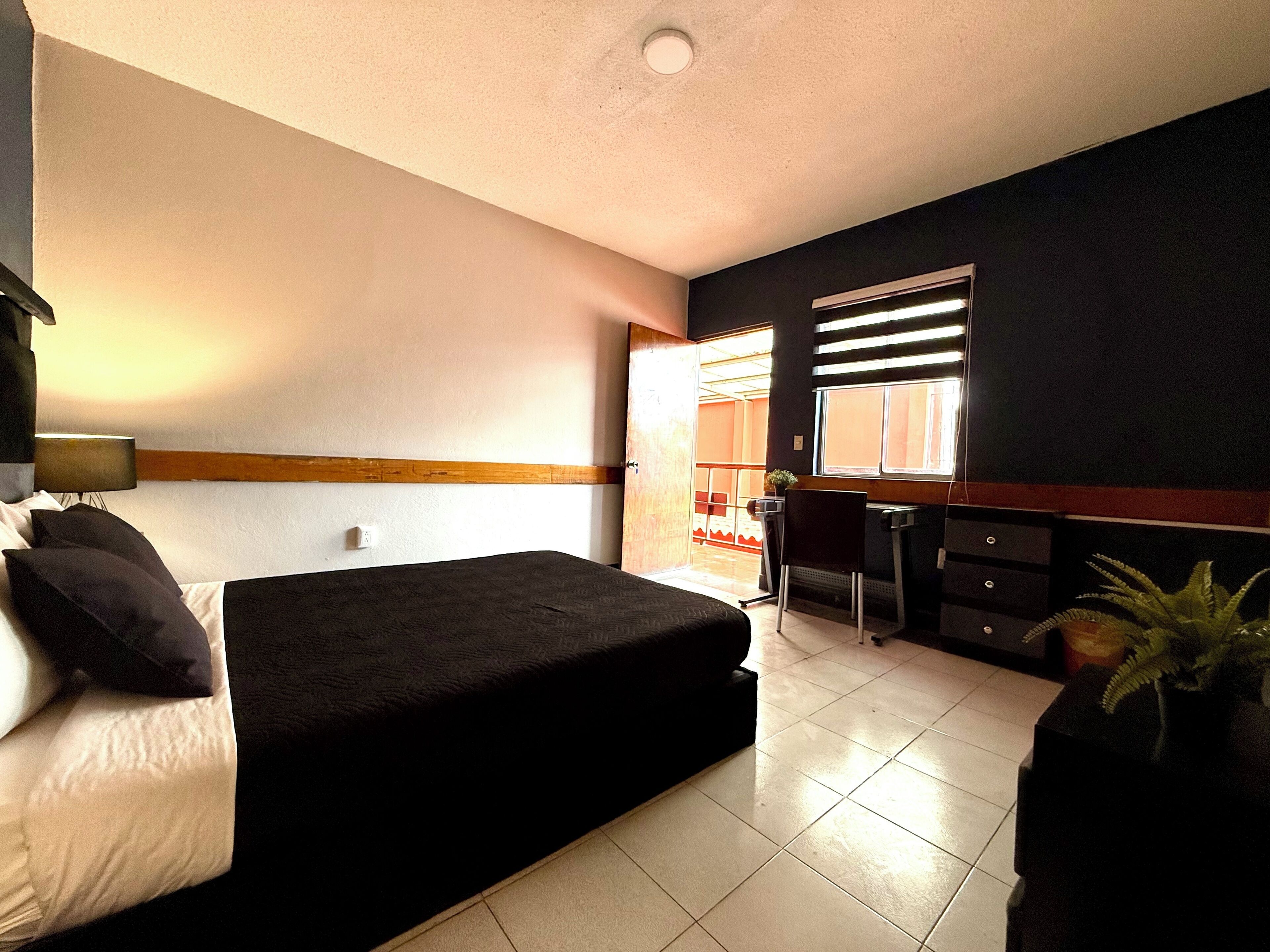 A bedroom with a bed, a desk, and a chair.