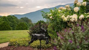Un jardín con una estatua de un caballo, rodeado de diversas plantas y flores.