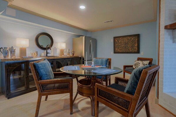 A dining area with a round glass table, four wicker chairs, a wooden cabinet, and a mirror on the wall. - Sunset Pointe - Fire Pit | Walking Trails & Creek! (Roseland)