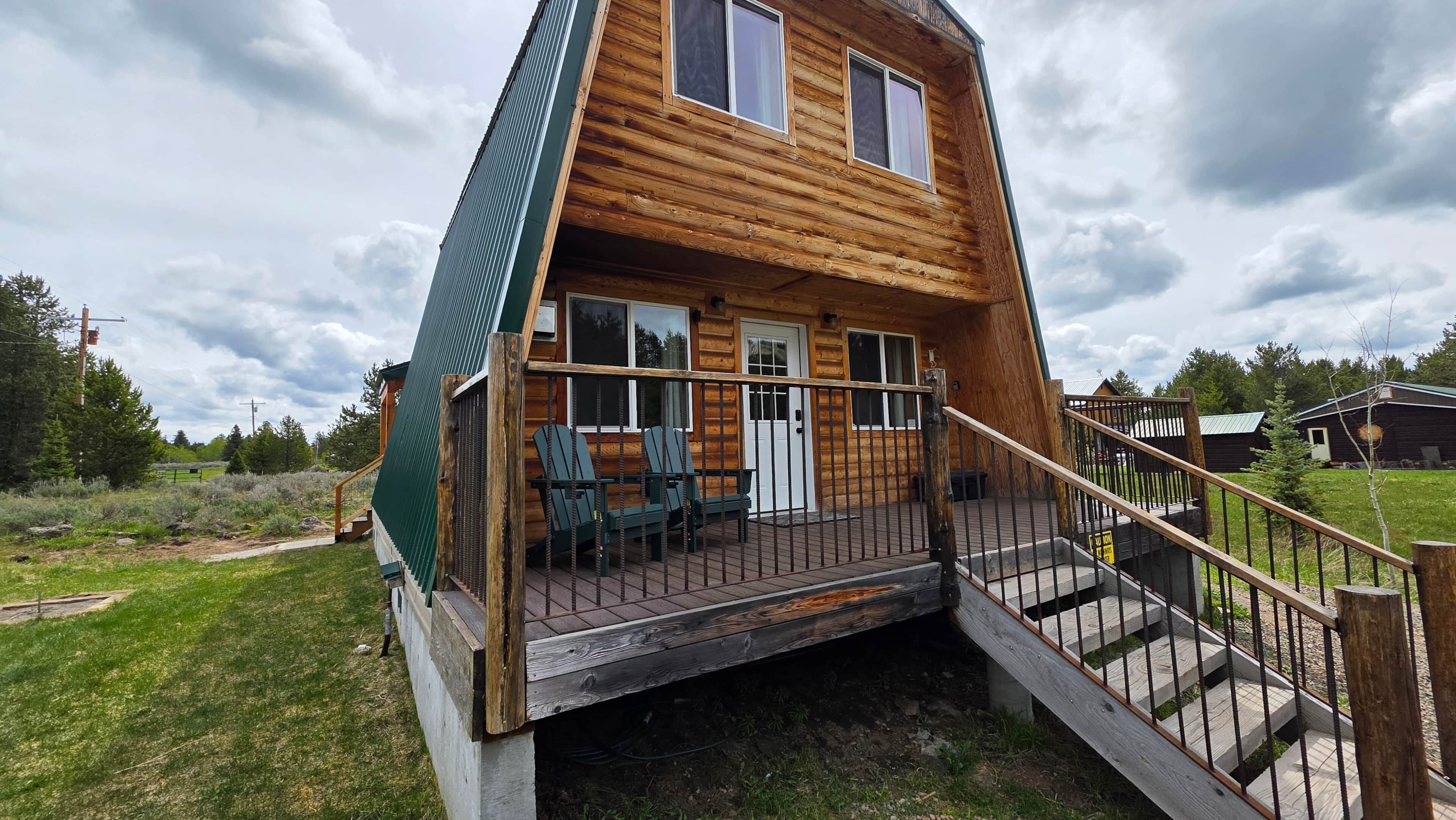 Puinen mökki, jossa on terassi, portaikko ja ovi.