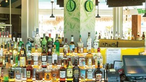 A bar area with a variety of liquor bottles, a cash register, and a sign that reads "Wasted away again". - Ocean & Mountain Views and Exclusive Beach Access in a Tropical Studio Suite (Rio Grande)