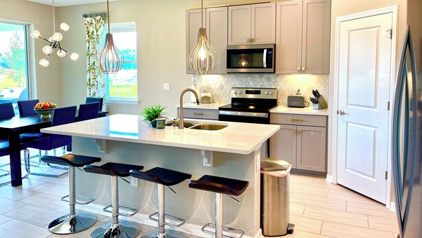 Una cocina moderna con una isla central, electrodomésticos de acero inoxidable y taburetes de bar.