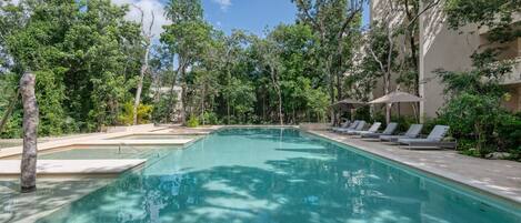 A swimming pool with lounge chairs and trees around it.