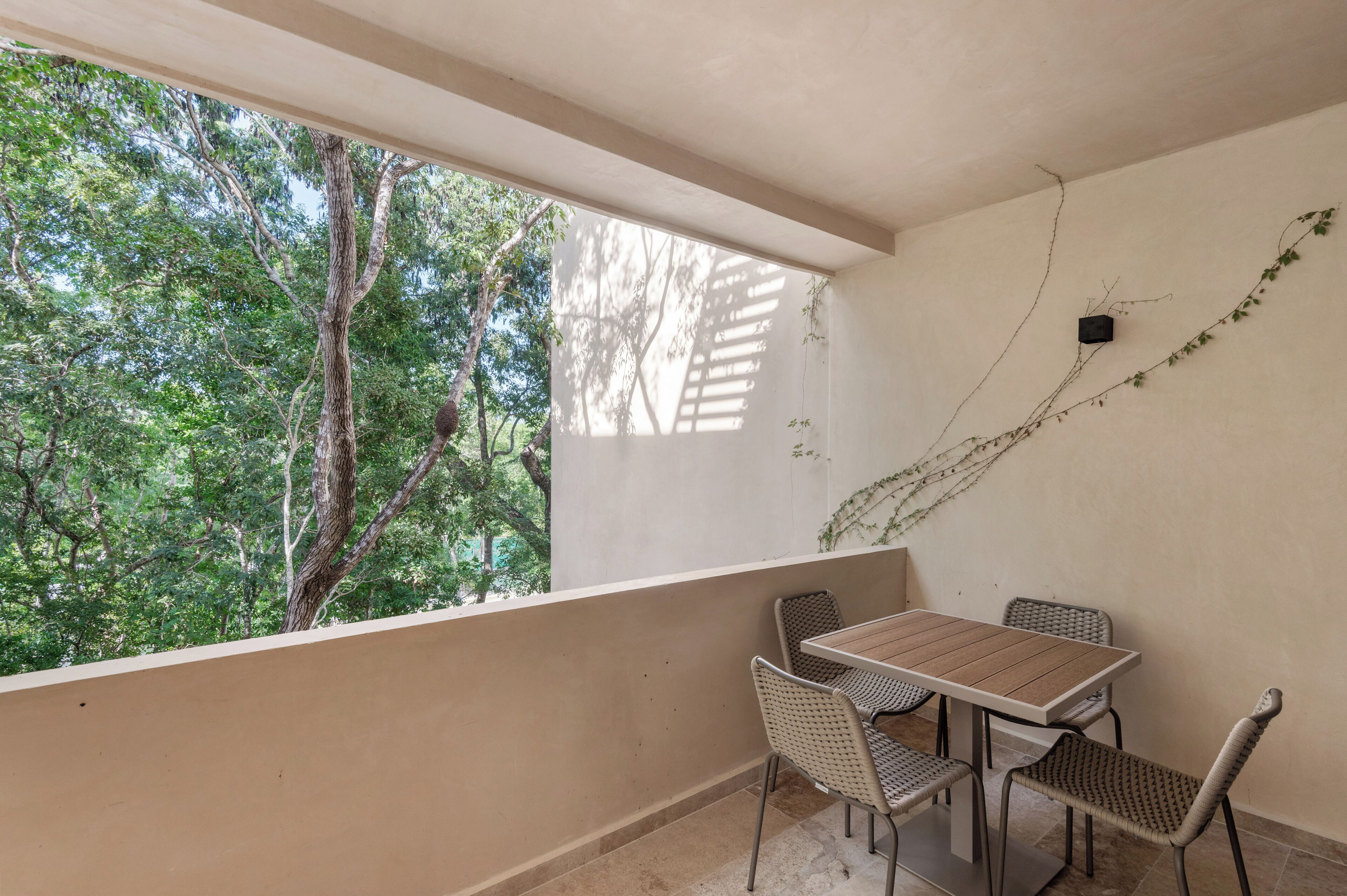 A balcony with a table and chairs, overlooking a forested area.