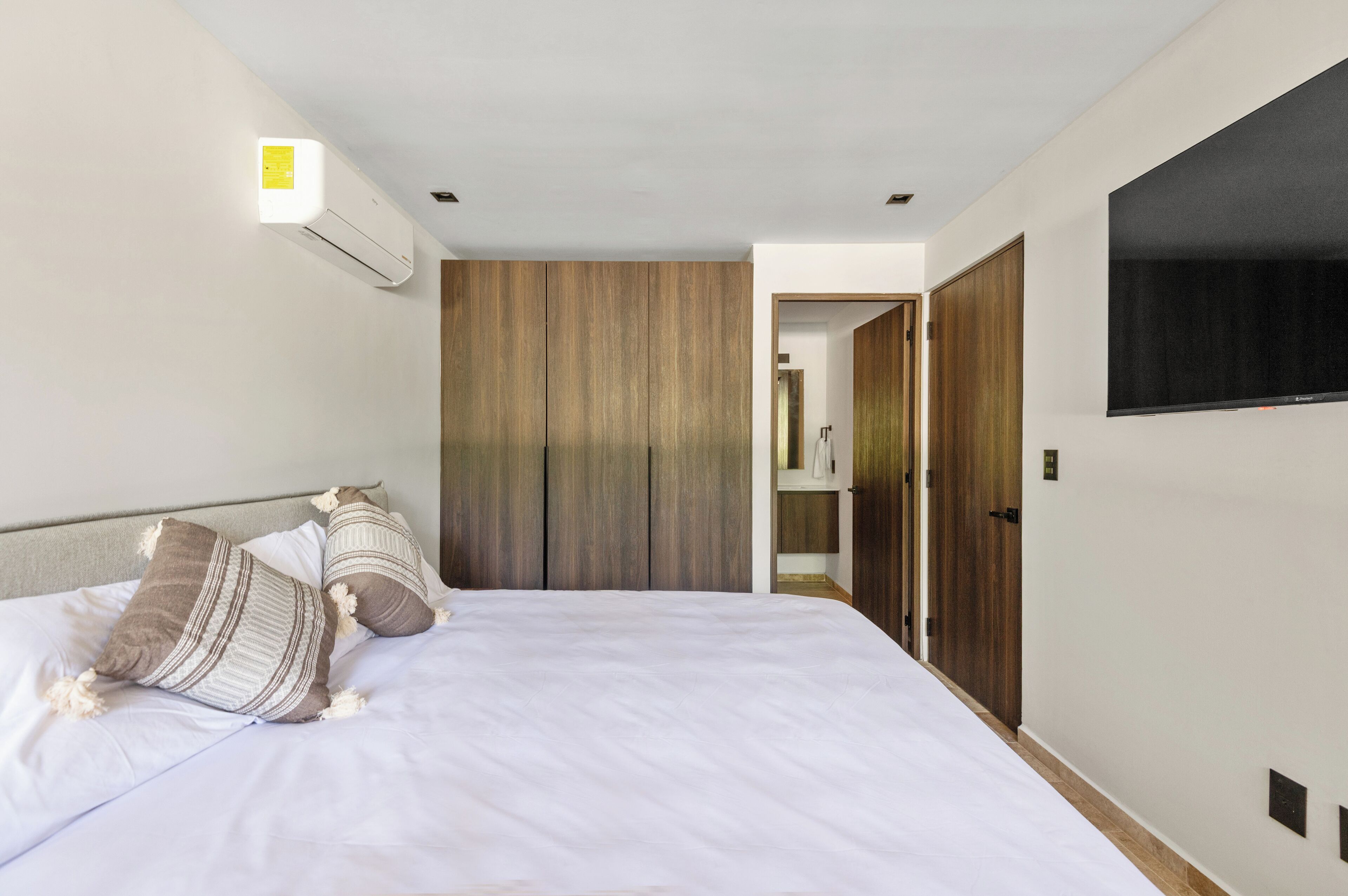 Quarto de hotel moderno com uma cama grande, televisão de tela plana e um guarda-roupa.