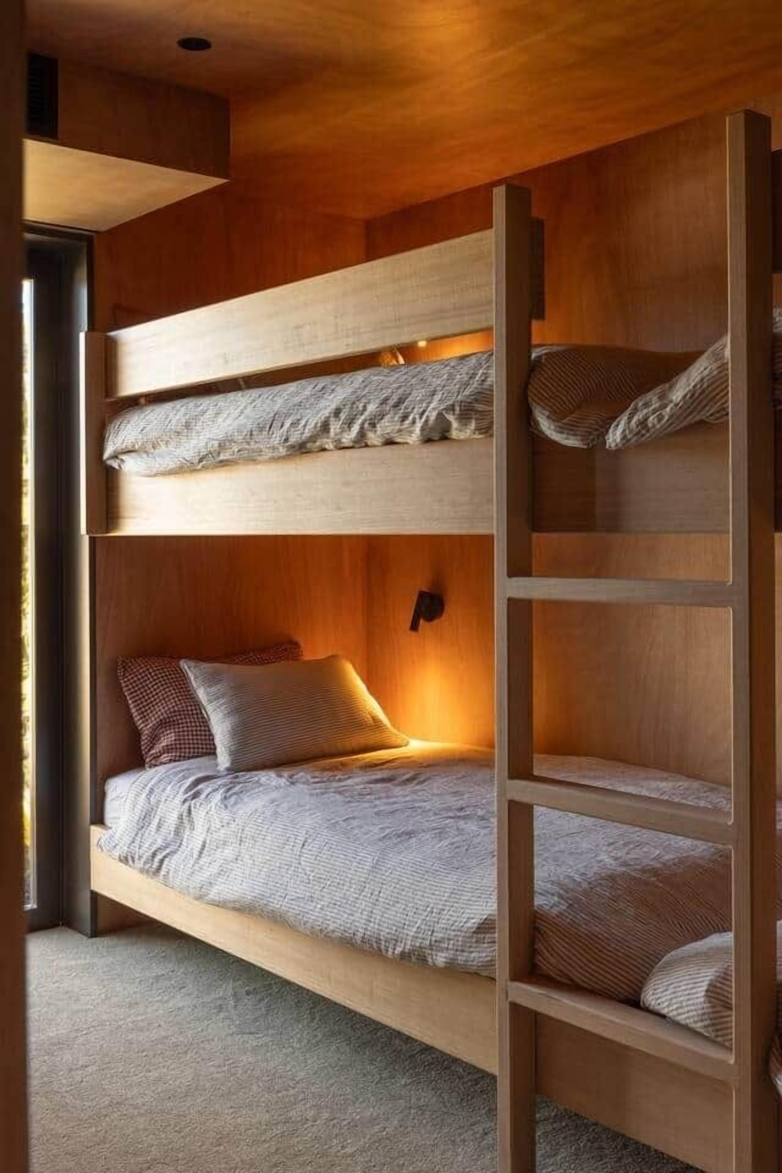 Een stapelbed met een houten trapje, hoofdbord en nachtkastje.