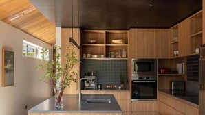 A modern kitchen with wooden cabinetry, a central island, and built-in appliances. - Redwood Cosy Hanmer Springs (Hanmer Springs)