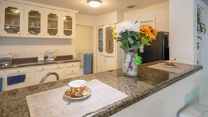 A modern kitchen with granite countertops, white cabinetry, and a refrigerator. - 8 Min ATandT Stadium | Central 4BR Retreat (Grand Prairie)