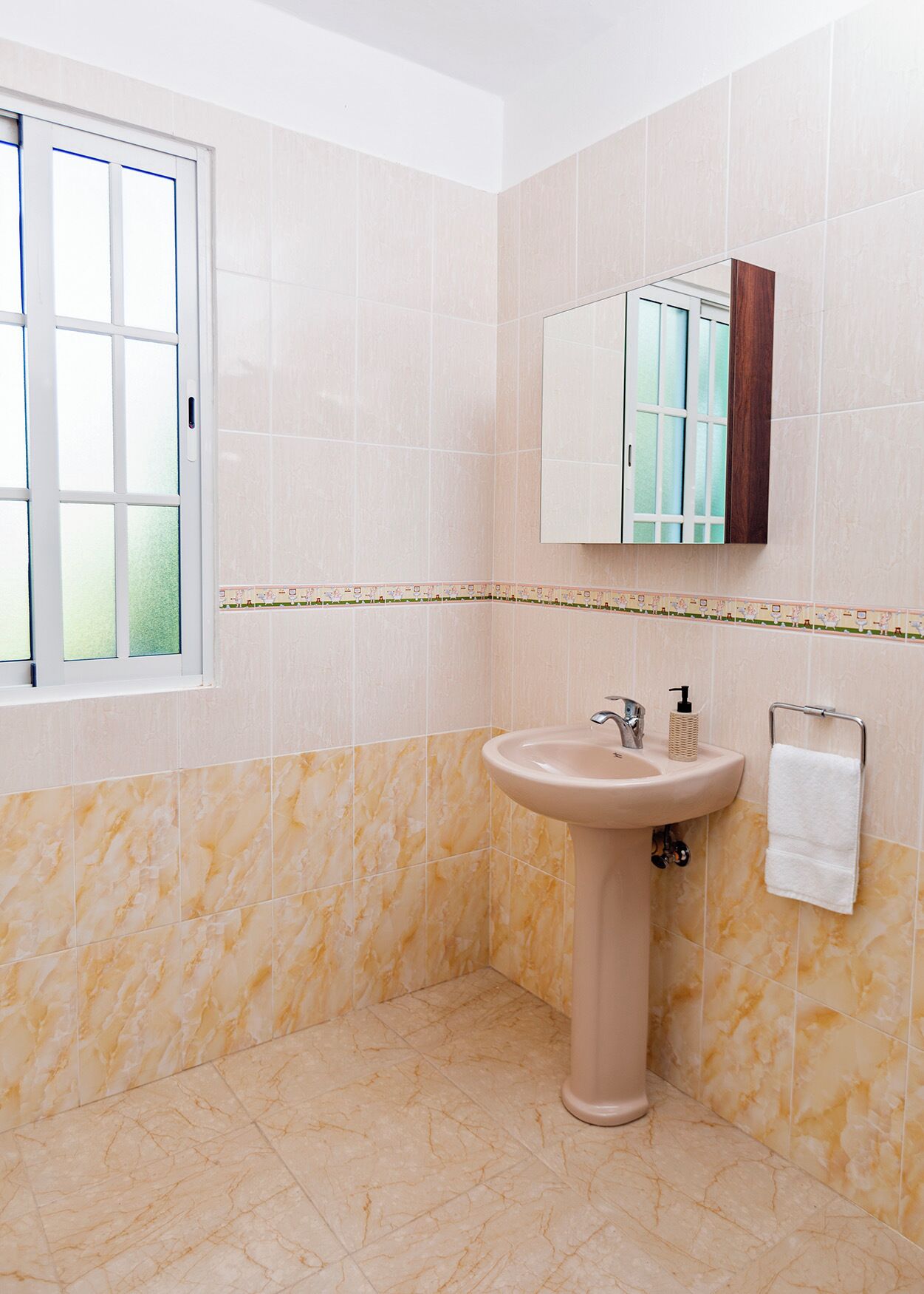 Een badkamer met een wastafel, spiegel en raam.