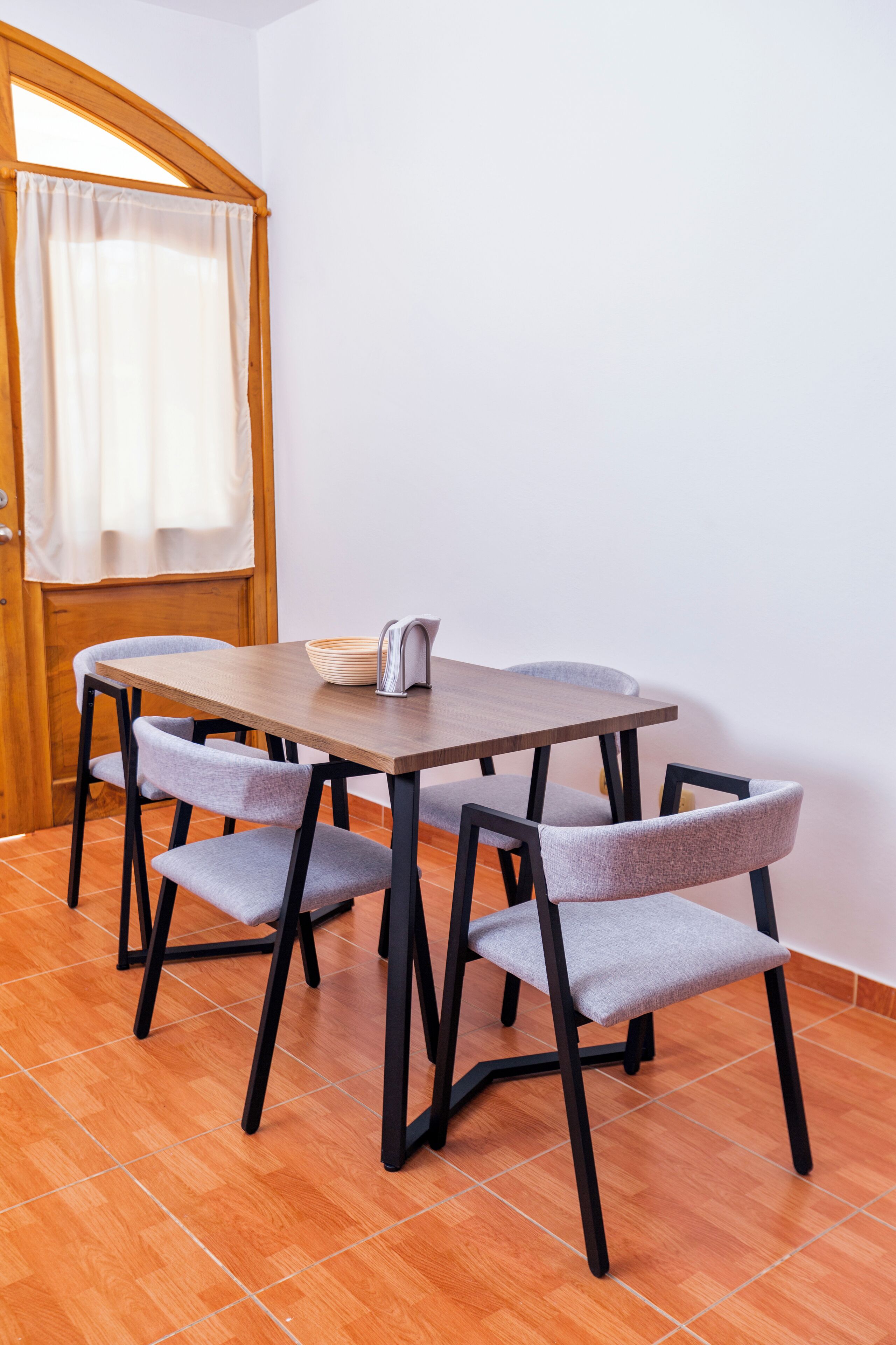 A dining area with a wooden table and four grey upholstered chairs.