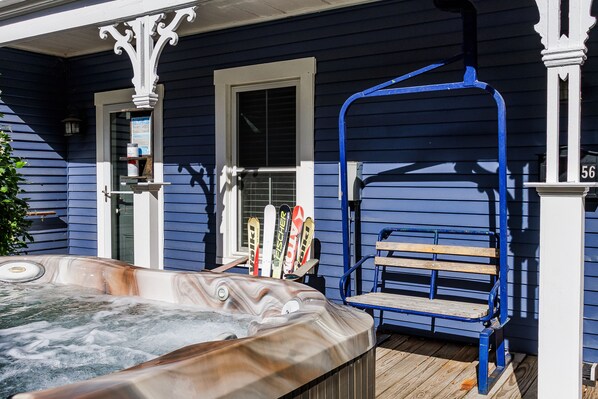 Een bubbelbad, een houten bank en een paar ski's voor een blauw huis.