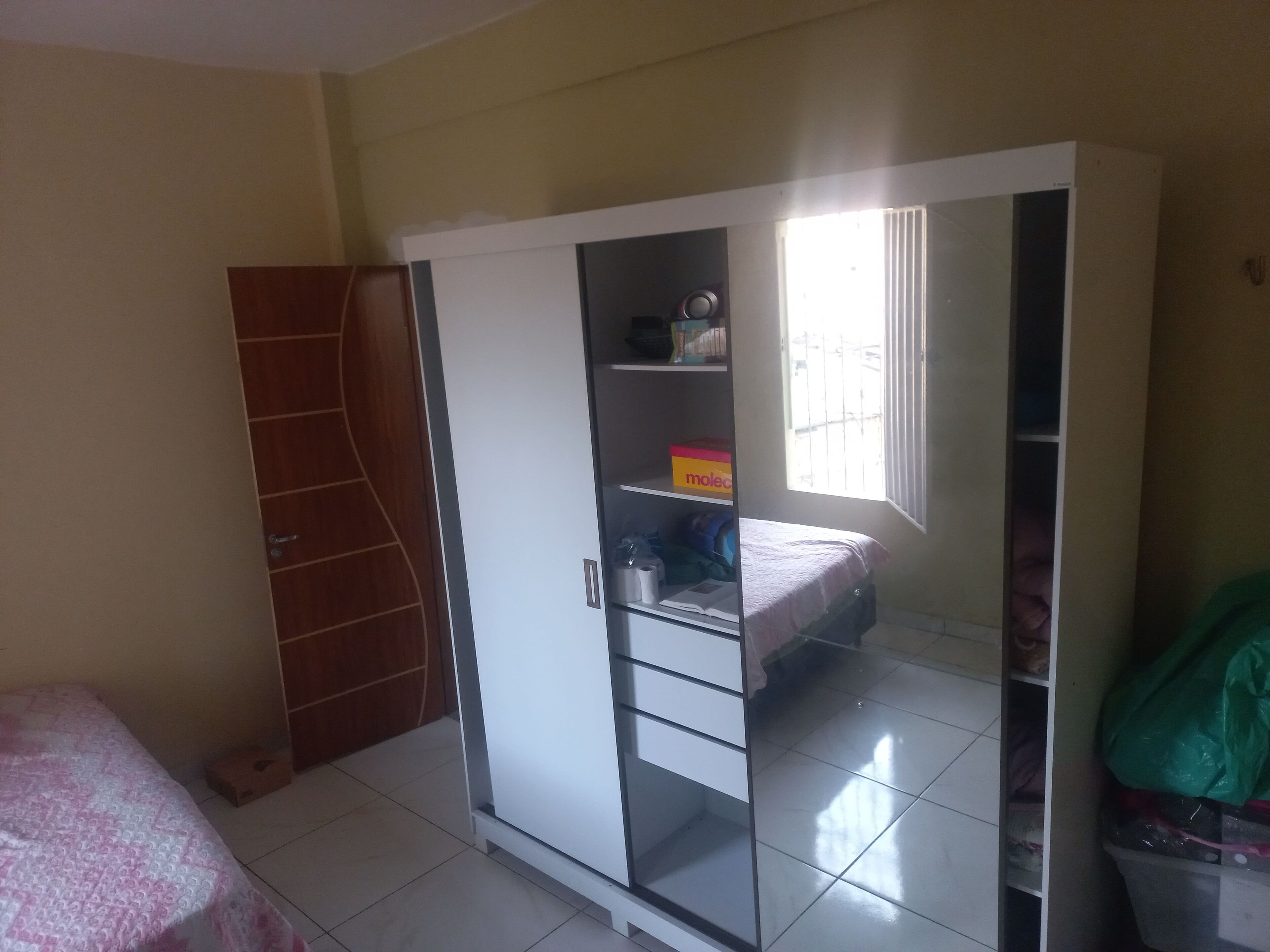 Una habitación con armario, cama y ventana.