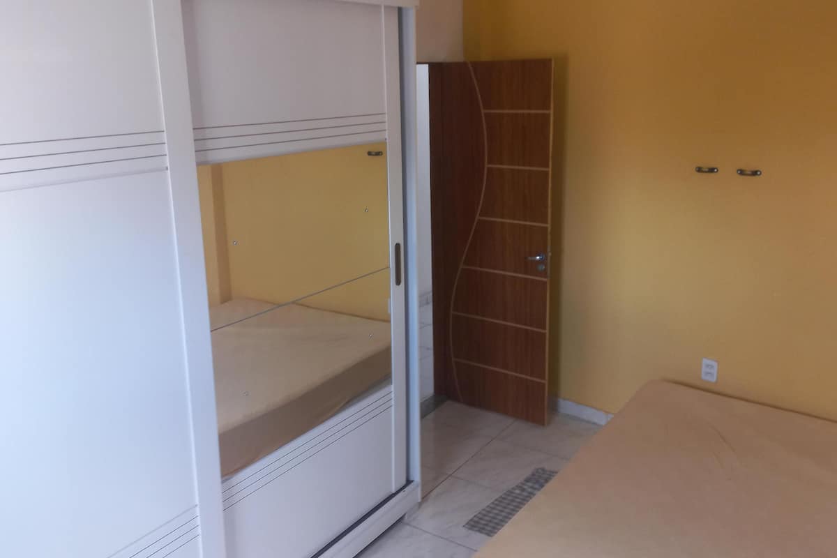 A room with a white wardrobe, a wooden door, and a tiled floor.
