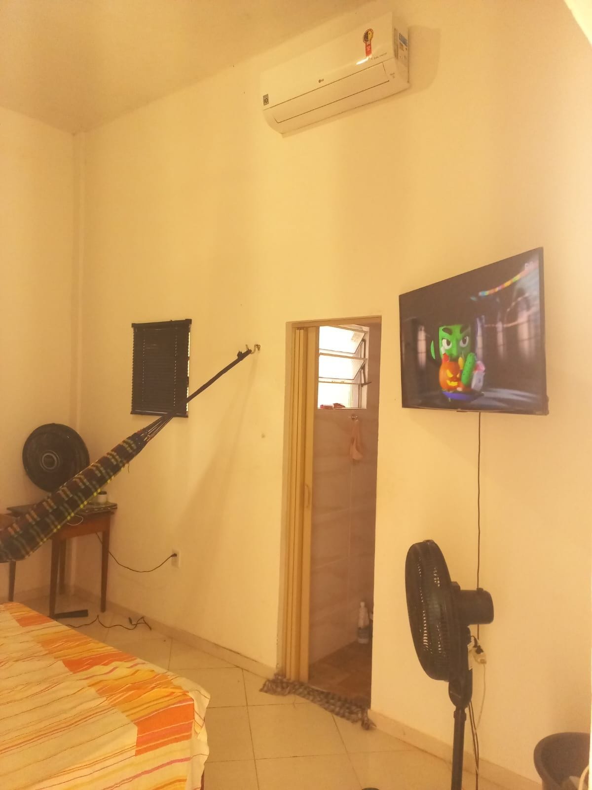 A room with a bed, a guitar, a television, and an air conditioner.
