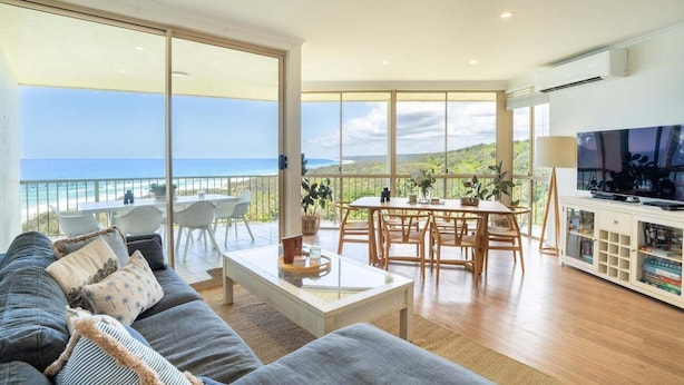 A spacious living room with a large sofa, a dining area, and a TV. - Breathtaking View! (Point Lookout)