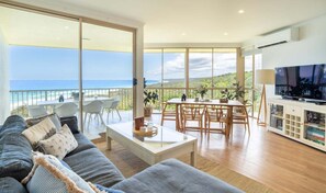 A spacious living room with a large sofa, a dining area, and a TV. - Breathtaking View! (Point Lookout)