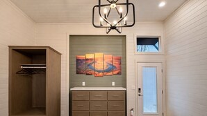 A bathroom with a wooden cabinet, a sink with a countertop, and a wall-mounted painting. - Ultra Luxury Tiny Home with Deck #1B (Page)