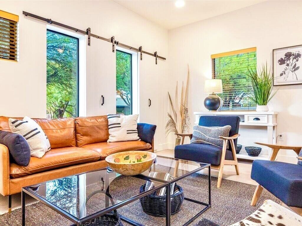 A modern living room with a leather sofa, a glass coffee table, and a blue armchair.