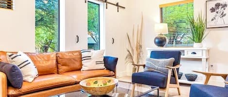 A modern living room with a leather sofa, a glass coffee table, and a blue armchair.