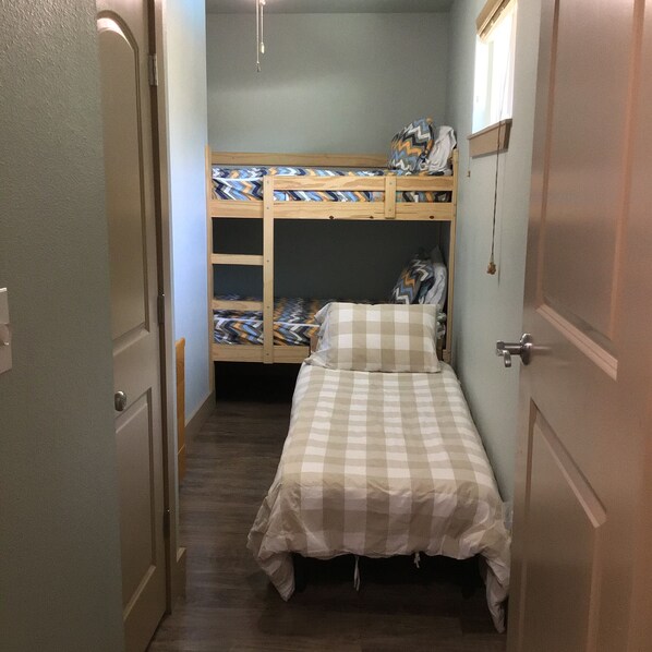 Een kleine kamer met een stapelbed en een enkel bed.