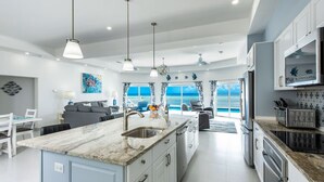 Een moderne keuken met een groot kookeiland, roestvrijstalen apparatuur en uitzicht op de oceaan.