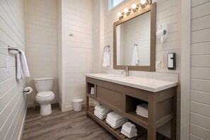 Ein Badezimmer mit einem Holzkonsolentisch, einer Toilette und einem beleuchteten Spiegel.