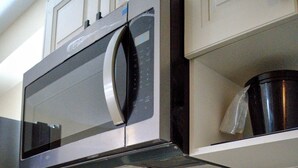 Una cocina con un microondas de acero inoxidable, una cafetera y un lavamanos.