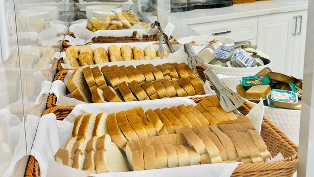 Un bufé de desayuno con panes, bollería y frutas variadas.