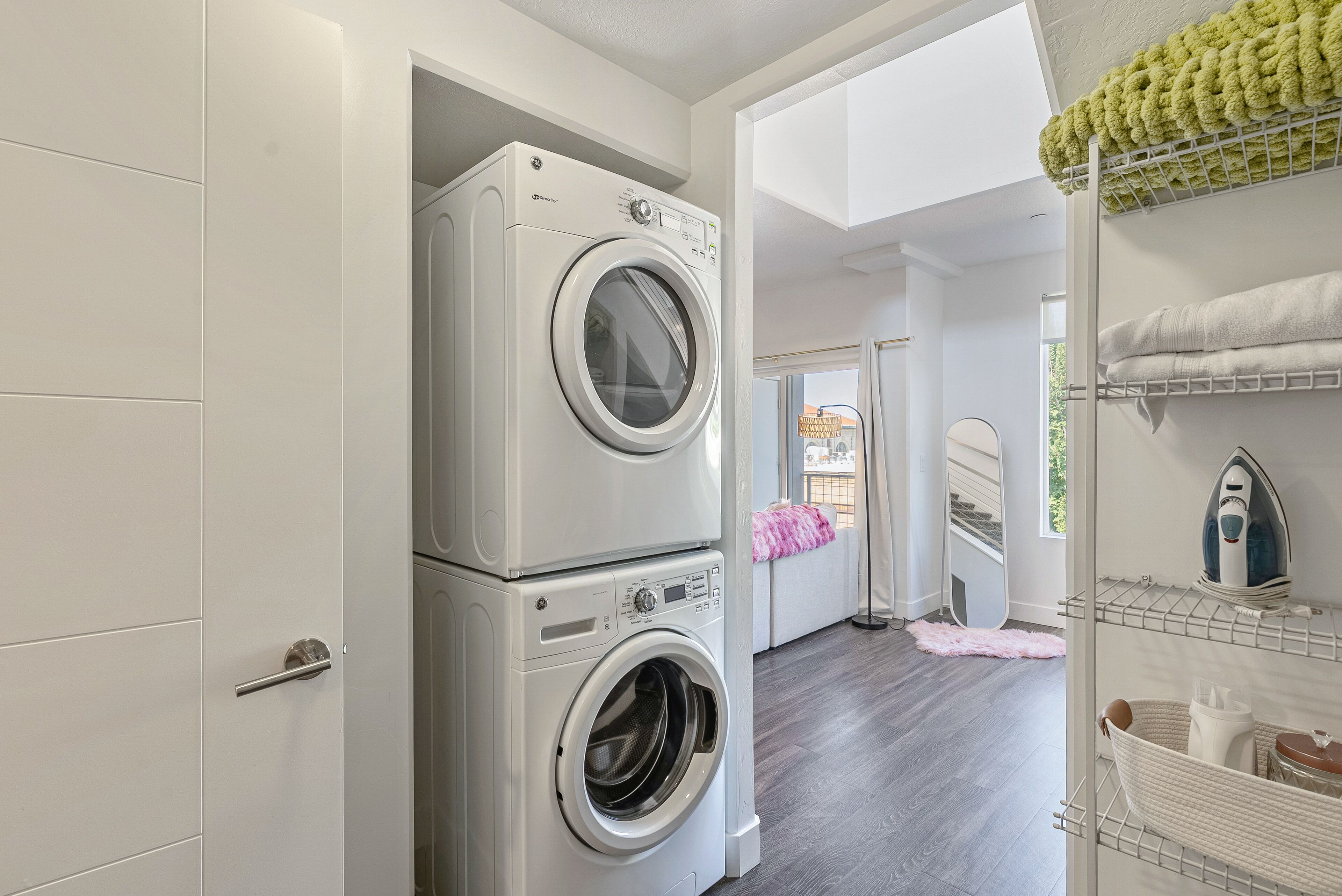 A laundry area with stacked washing machines and a drying rack with towels.