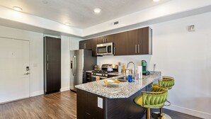 A modern kitchen with dark wooden cabinets, stainless steel appliances, and a granite countertop. - NEW-KING Bed Loft Apartment / Downtown/ Free Garage Parking/ GYM (Salt Lake City)